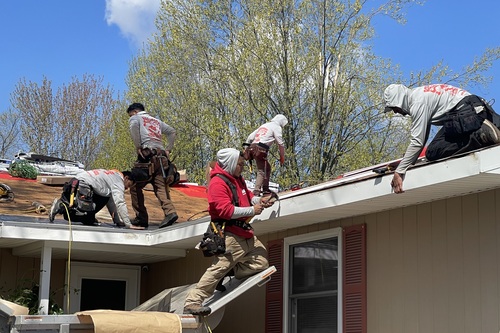 Roofing contractors working on an Ann Arbor home during a summer day.