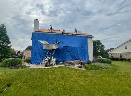 Blue tarp laid over a new roof being laid.