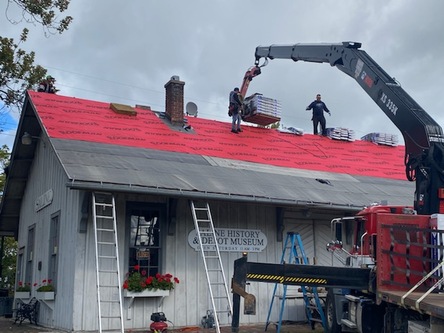 Red tarp laid over roof being laid by Roofman.