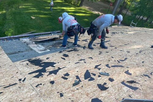 Individuals working on a roof with Roofman. 
