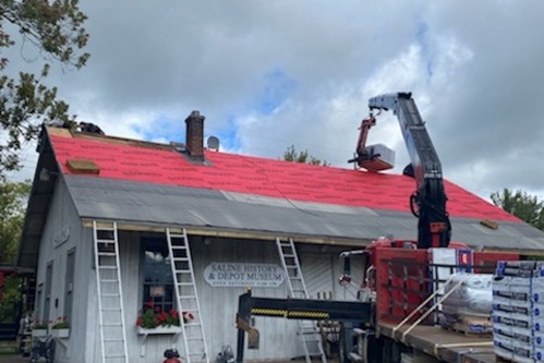 Installation of a roof with red tarp overlay. 