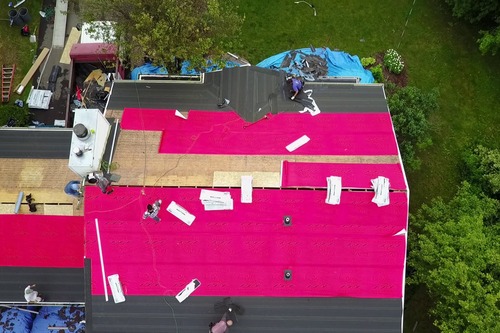 Ariel overview of red roof tarp laid over a roof job. 
