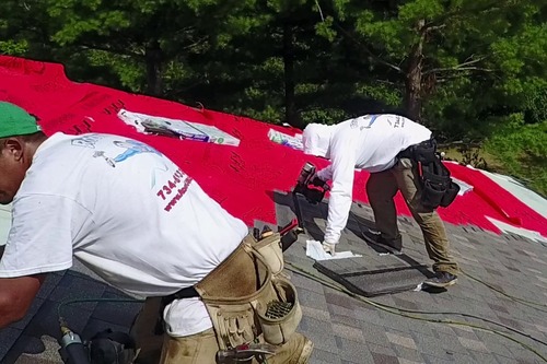 Workers on roof with red tarp. 